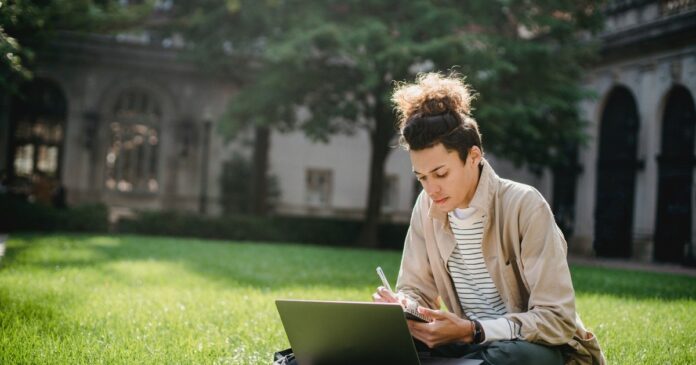 person-sitting-on-the-grass-taking-notes-at-a-laptop.jpg